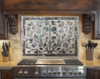 Può includere: Un paraschizzi rettangolare in marmo con un motivo floreale sopra un fornello in acciaio inossidabile. Il design presenta motivi floreali blu, argento e marroni su uno sfondo di marmo bianco. Il paraschizzi è incorniciato da un bordo decorativo.