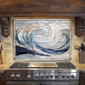 May include: Stained glass panel depicting a stylized ocean wave in shades of blue, white, and beige. The artwork is framed and mounted above a stainless steel stove in a kitchen setting. The wave design is a prominent feature.