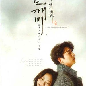 Op de afbeelding: Poster voor de Zuid-Koreaanse televisieserie "Goblin: The Lonely and Great God". De afbeelding toont een man en een vrouw, waarbij de vrouw haar hoofd op de schouder van de man laat rusten. De poster bevat Koreaanse tekst en de Engelse titel.