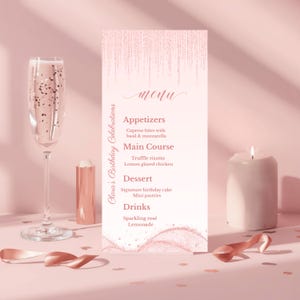 May include: A pink menu card with the text "menu" and a list of appetizers, main course, dessert, and drinks. A champagne flute, candle, and decorative ribbon are on a pink surface.