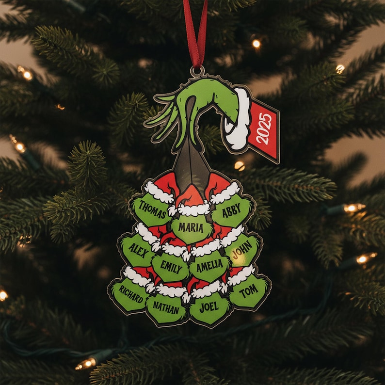 May include: A Christmas tree ornament featuring a green hand and a red and white Santa hat design. The ornament has a tag that says "2025". Names are printed on green heart-shaped ornaments, including Thomas, Maria, and Abby.