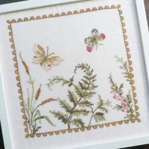 May include: A white framed embroidery featuring a butterfly, fern, and wildflowers in shades of green, brown, and pink.