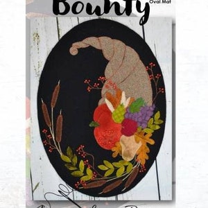 May include: A felt applique pattern for a 14" x 19" oval mat called "Bounty". The design features a cornucopia filled with fruit and vegetables, surrounded by leaves and berries.
