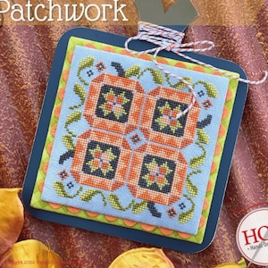 May include: A cross-stitch design of a pumpkin patchwork with orange, green, and blue colors. The design is framed in a dark blue frame with a light blue mat. The title "Pick Your Pumpkin Patchwork" is displayed above the design.