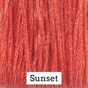May include: Close-up of a spool of coral-colored embroidery floss. The floss is made of cotton and has a soft, fuzzy texture. The label on the spool reads "Sunset".