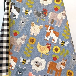 May include: A blue quilt featuring a farm animal theme. The quilt depicts a variety of animals, including cows, pigs, horses, chickens, and sheep. The animals are all in a pixelated style and are surrounded by sunflowers and other floral designs.