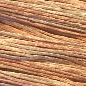 May include: Close-up of a bundle of soft, peach-colored embroidery floss with a subtle shimmer.