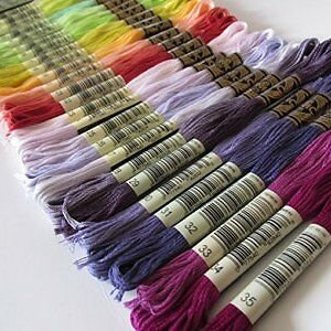 May include: A collection of embroidery floss spools in various colors, including green, yellow, orange, pink, purple, and blue. The spools are labeled with numbers from 32 to 35.