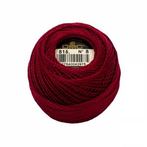 May include: A ball of DMC embroidery floss in a deep burgundy color. The label shows the number 815 and the number 8. The barcode is visible. This thread is used for various embroidery and needlework projects.