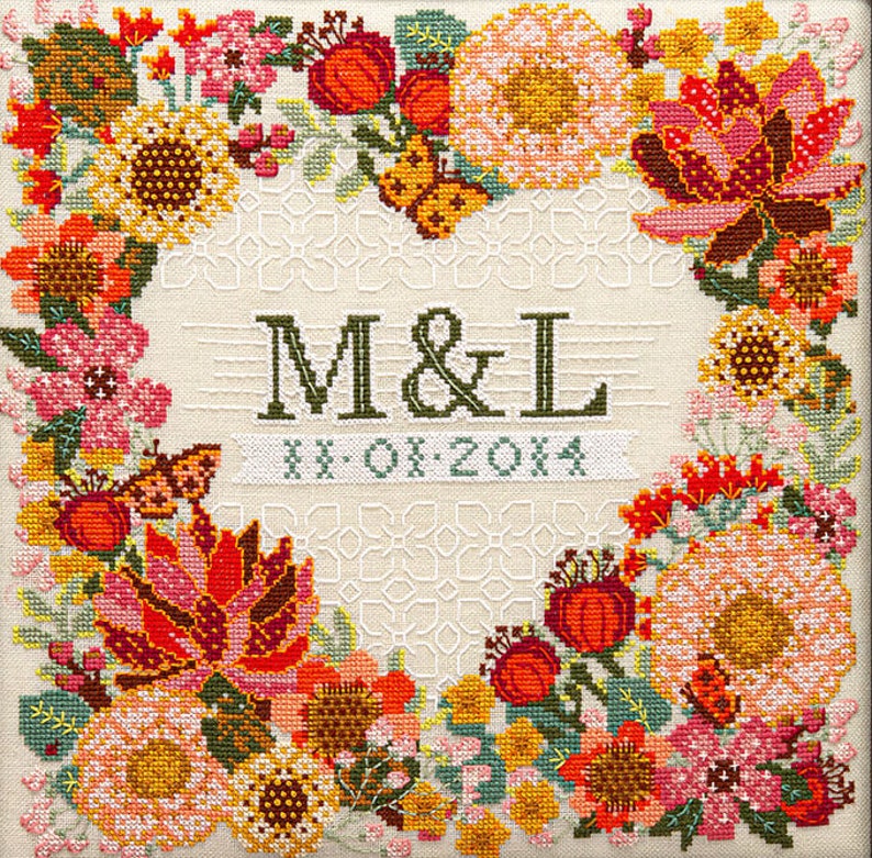 Pu&ograve; includere: Un ricamo floreale a punto croce con sfondo color crema e bordo floreale quadrato nei toni del rosso, arancione, rosa e giallo. Il disegno include le iniziali "M & L" e la data "11-01-2014".