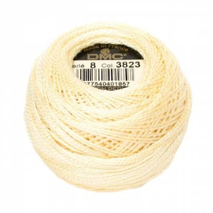 May include: A ball of cream-colored DMC Perle cotton thread, size 8, with a product label visible. The label includes the text "Made in France", the DMC logo, and a barcode. The thread is tightly wound.