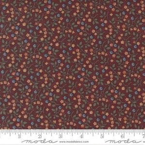 May include: A dark burgundy fabric featuring a repeating pattern of small, muted orange flowers, green leaves, and tiny blue berries on thin, winding stems. A white ruler is visible at the bottom, showing a scale of 7 inches.