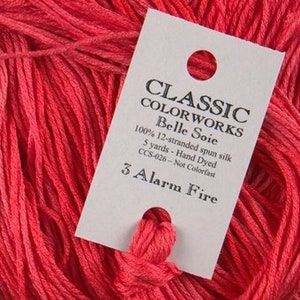 May include: A skein of 100% 12-stranded spun silk embroidery floss in a bright red color called "3 Alarm Fire". The floss is 5 yards long and is hand-dyed. It is not colorfast. The label also states "Classic Colorworks Belle Soie" and "CCS-026".