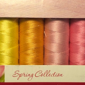 May include: A set of 10 spools of thread in pastel colors, including light green, yellow, orange, pink, and purple. The spools are labeled "Spring Collection" and "Mettler".
