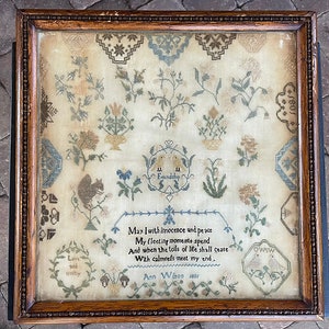 May include: An antique framed sampler with a variety of embroidered floral motifs, birds, and a squirrel. The sampler includes the text "May I with innocence and peace My fleeting moments spend And when the toils of life shall cease With calmness meet my end, Ann Wilson seo1".