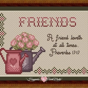 May include: Cross-stitch artwork in a wooden frame. The design features the word "FRIENDS" in red, a pink and purple watering can with flowers, and the quote "A friend loveth at all times. Proverbs 17:17."