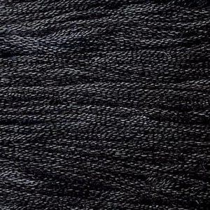 May include: Close-up of a bundle of black and gray yarn. The yarn appears to be tightly wound, with a textured surface. The color is a mix of dark black and lighter gray, creating a subtle contrast.