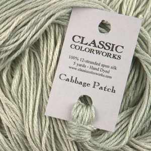 May include: A skein of light green 100% silk yarn, hand-dyed in a shade called "Cabbage Patch". The yarn is 12-stranded and comes in a 5-yard skein. The label is from Classic Color Works.