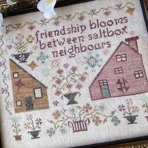 May include: Cross-stitch sampler with a quote: "Friendship blooms between saltbox neighbours". The sampler features two small houses, flowers, and a variety of other details.