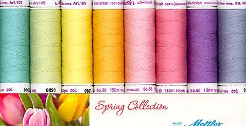 May include: A collection of 10 spools of thread in various pastel colors, including light blue, green, yellow, orange, pink, and purple. The spools are labeled "Spring Collection" and "Mettler".