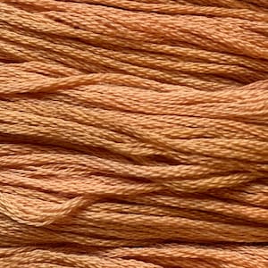 May include: Close-up of a bundle of peach-coloured embroidery floss. The threads are tightly wound, creating a textured surface. The colour varies slightly, with some areas appearing lighter than others.
