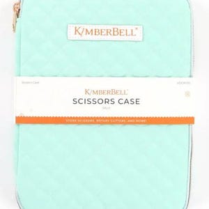 May include: A mint green quilted scissor case with a zipper closure. The case has a white label with the text "K/MBERBELL SCISSORS CASE Mint" and the text "STORE SCISSORS, ROTARY CUTTERS AND MORE!"