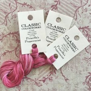 May include: Three skeins of pink embroidery floss with white accents. The floss is labeled "Classic Colorworks" and "Priscilla's Peppermint".