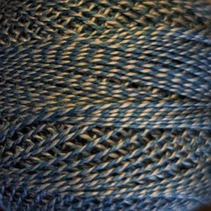 May include: Close-up of a skein of yarn with a blue and beige variegated color pattern.