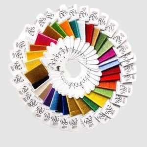 May include: A circular display of colorful embroidery floss samples. The floss is arranged in a fan shape, showcasing a variety of colors including gold, red, green, and blue. Each sample is attached to a white card with text and a logo.