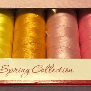 May include: A set of 10 spools of thread in pastel colors, including light green, yellow, orange, pink, and purple. The spools are labeled "Spring Collection" and "Mettler".