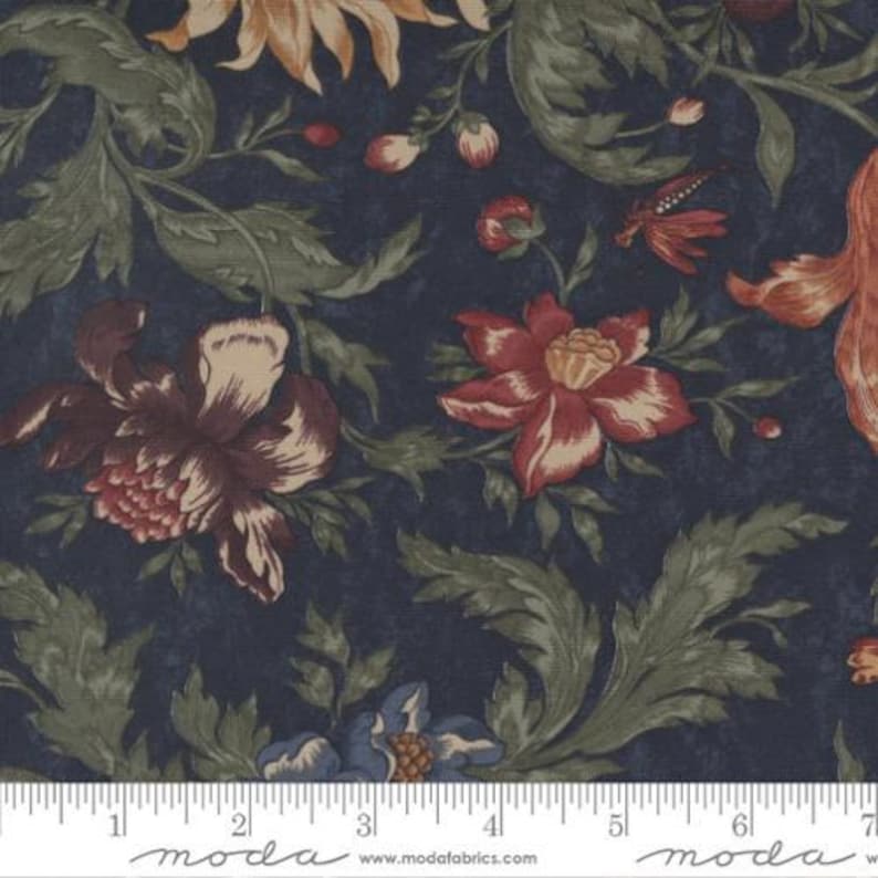 May include: A dark navy blue fabric featuring a repeating floral pattern with large blossoms in shades of deep red, muted orange, and cream, accented by sage green foliage. A white ruler is visible at the bottom, showing 7 inches.
