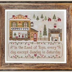 May include: A cross-stitch pattern featuring a winter scene with a toy shop called "Geppetto's" and a workshop. The text "In the Land of Toys, every day except Sunday is Saturday." is included in the design.