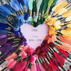 May include: A heart-shaped arrangement of DMC embroidery floss in various colors, ranging from blue to red. The floss is arranged in a rainbow pattern, with the colors transitioning smoothly from one to the next. The text "DMC Colors: 400-598" is written in black on a pink background in the center of the image.