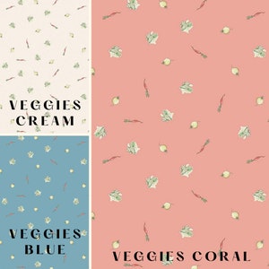 May include: Three fabric swatches with a repeating pattern of watercolour vegetables. The background colours are cream, blue, and coral. The text "VEGGIES CREAM", "VEGGIES BLUE", and "VEGGIES CORAL" are printed on the swatches.