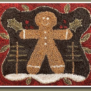 May include: A brown gingerbread man with white icing eyes and a red background. The gingerbread man is standing in front of two green holly bushes.