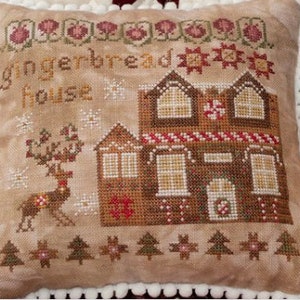 May include: A brown and tan embroidered pillow with a gingerbread house, a reindeer, and the text "gingerbread house".