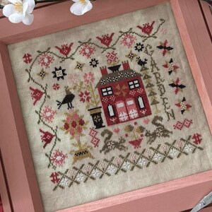May include: Cross-stitch embroidery of a red house with white trim and a black bird, surrounded by flowers and greenery. The text "GARDEN" is stitched in the upper right corner.