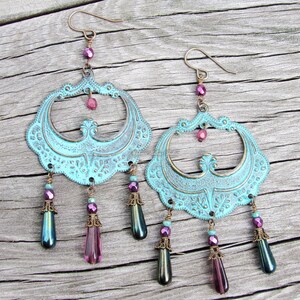 May include: A pair of turquoise blue earrings with ornate metalwork and dangling iridescent and purple beads.