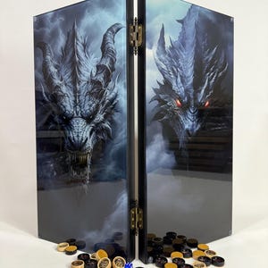 Może przedstawiać: Dwupanelowa składana plansza do gry z ilustracją smoka w odcieniach niebieskiego i szarego. Plansza jest zawiasowa z mosiężnym osprzętem i zawiera czarne, brązowe i złote elementy gry. Gra o tematyce fantasy.