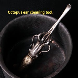 May include: A silver ear cleaning tool with an octopus design. The tool has a spoon-like end and a decorative octopus body with tentacles. The text "Octopus ear cleaning tool" is in yellow.