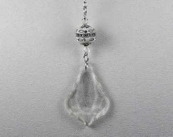 May include: A clear crystal pendant with a silver chain and a decorative silver bead. The pendant is teardrop-shaped and hangs from a silver chain with a decorative silver bead and small clear crystals.