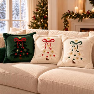 May include: Three square throw pillows featuring embroidered Christmas tree designs. One dark green pillow with a red tree motif, and two cream-coloured pillows with white tree motifs. Each tree is topped with a gold star and a bow.