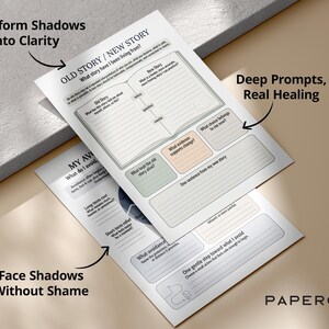 May include: Two white paper worksheets with text and prompts for self-reflection. The top sheet reads "OLD STORY / NEW STORY" and "Transform Shadows Into Clarity." The bottom sheet says "Face Shadows Without Shame."