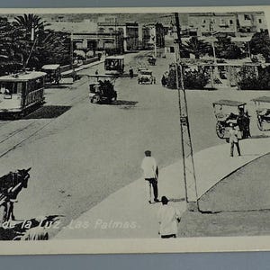 Op de afbeelding: Vintage zwart-wit ansichtkaart met een straatbeeld in Las Palmas. De afbeelding toont een straat met een tram, paardenkoetsen en voetgangers. De tekst "Puerto de la Luz. Las Palmas" is zichtbaar.