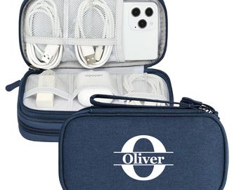 May include: Navy blue travel organizer with white cables, a phone, and accessories. The case is open, revealing compartments for electronics. The exterior features the name "Oliver" with a large initial "O".