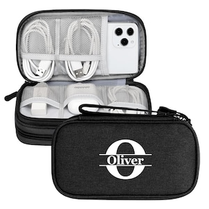 May include: Black travel organizer with a zippered closure, containing white charging cables, a white smartphone, and other electronic accessories. The front of the organizer features the name "Oliver" in white.