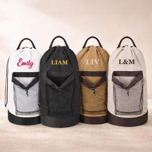 May include: Four personalized drawstring bags in white, black, tan, and light gray. Each bag has a mesh pocket and a handle. The bags are labeled with names: "Emily", "LIAM", "LIV", and "L&M".