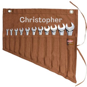 May include: A brown canvas tool roll with the name "Christopher" embroidered in white. The roll contains a set of shiny, silver wrenches of varying sizes. A small tag with the brand name is visible.