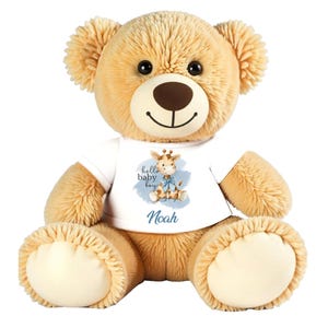 May include: A tan teddy bear wearing a white t-shirt with a giraffe illustration and the text "hello baby boy" and "Noah". The bear has a round, brown nose and black eyes. The bear's fur is soft and fluffy.