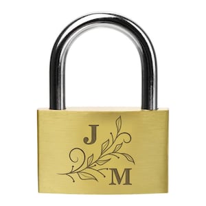 May include: A gold-colored padlock with a silver-colored shackle. The padlock is engraved with the letters "J" and "M" and a decorative floral design. The background is plain white.